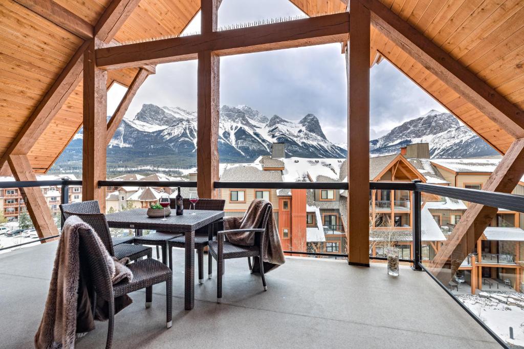 balcone con tavolo, sedie e montagne di Luxury Penthouse At Solar A Resort And Spa a Canmore