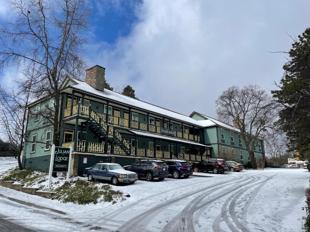 a green building with cars parked in the snow at Julian Lodge in Julian