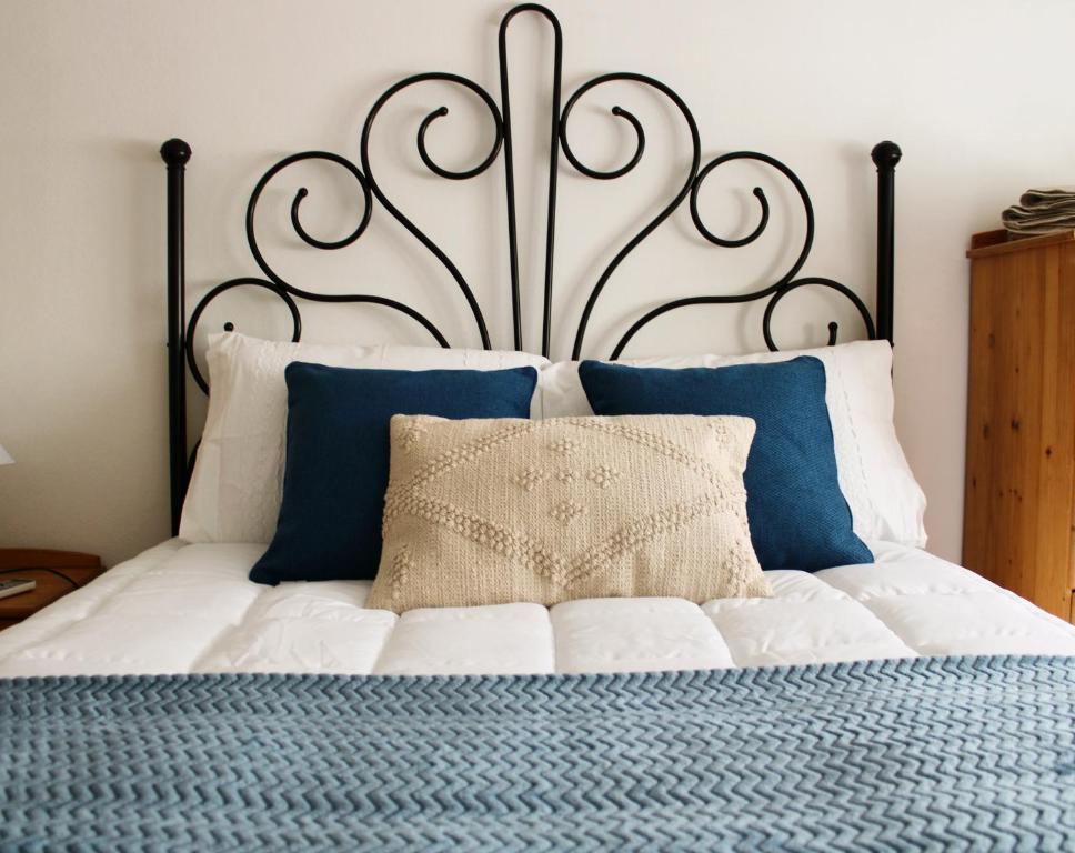 a white bed with a large headboard with blue pillows at Casa da Cal Branca in Évora