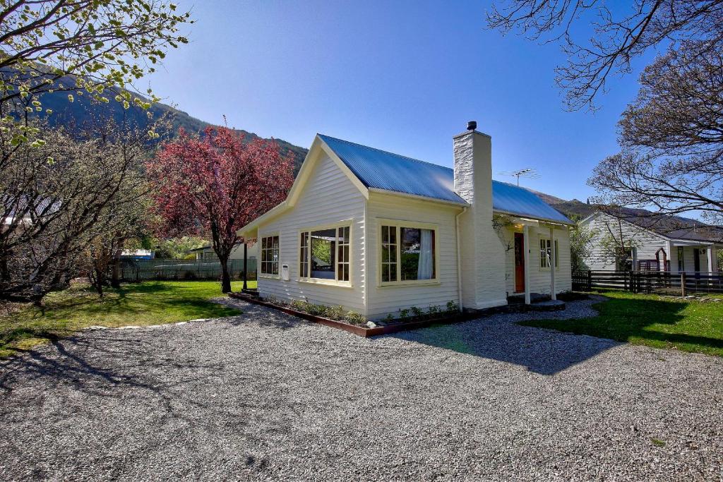 a small white house with a blue roof at Aberdeen Cottage - Nestled in the Heart of Arrowtown - New! in Arrowtown