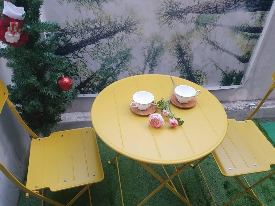 a yellow table and chairs with two cups and flowers on it at AREX Hongik univ Unit 201 in Seoul