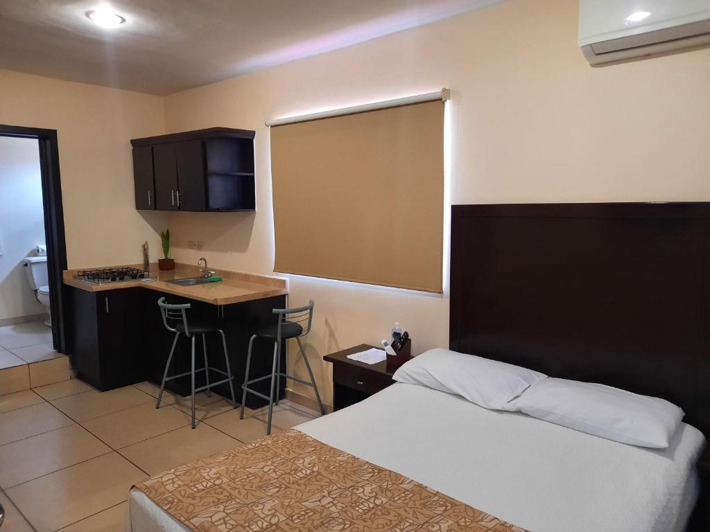 a hotel room with a bed and a desk and a kitchen at Suites Hgen in Los Mochis