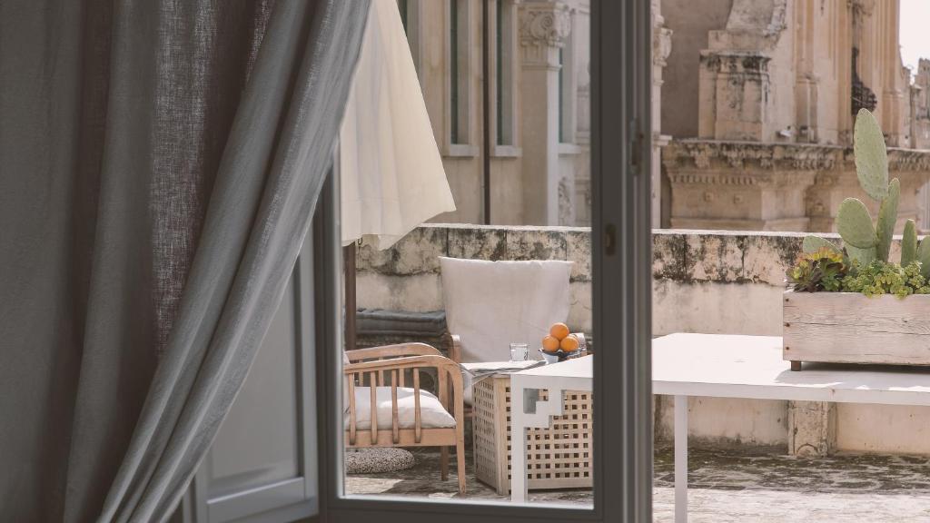 a room with a window with a table and a chair at Palazzo Trigona Suites in Noto