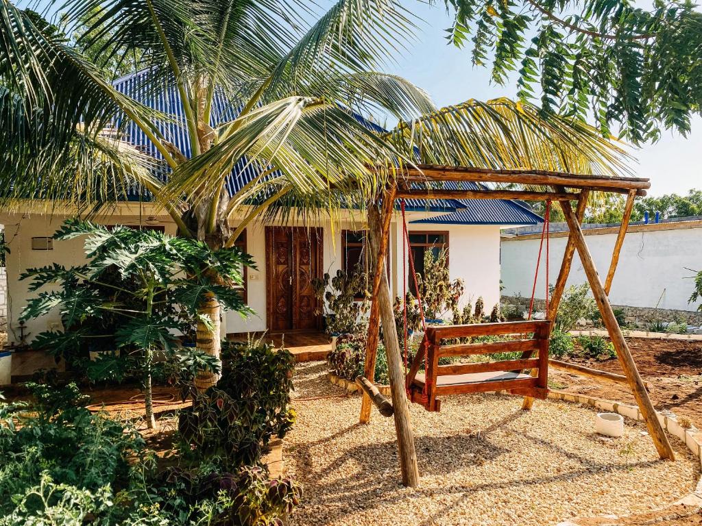 a swing in front of a house with a palm tree at Cozy private villa in Fukuchani in Mchangani