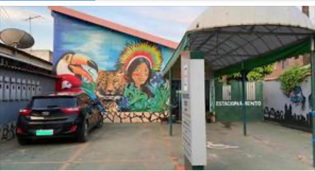 une voiture garée devant un bâtiment avec une fresque murale dans l'établissement Engenheiros Hotel - Porto Velho, à Porto Velho