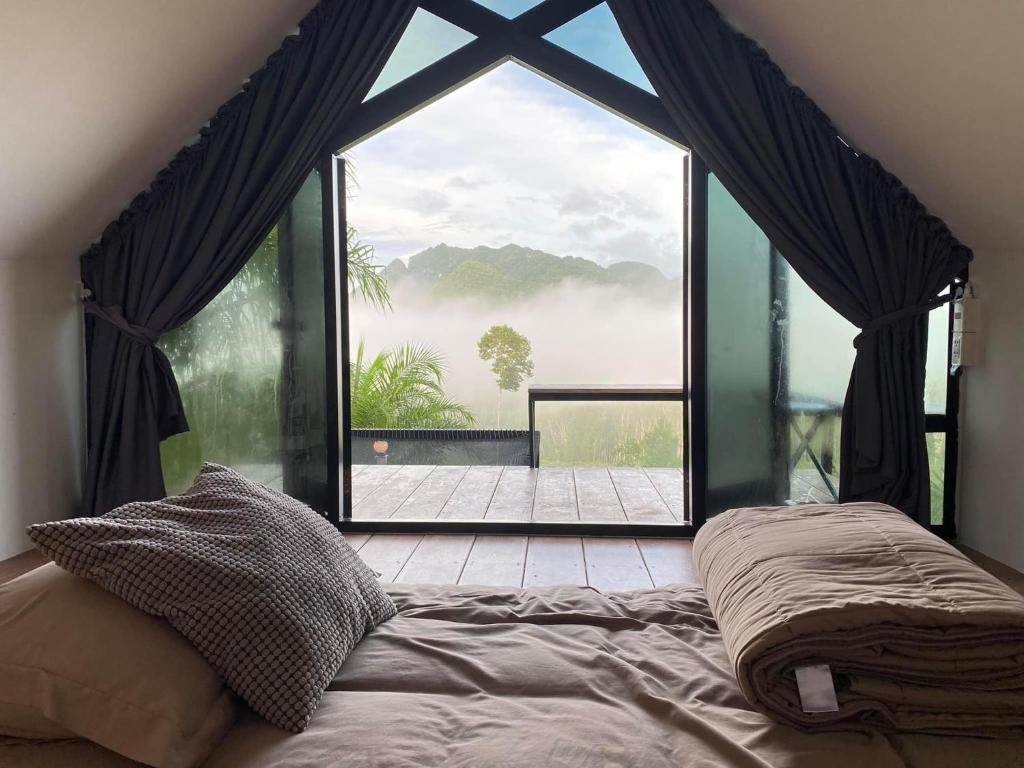 a bed in a room with a large window at Por Sampao Camp&Resort in Ban Pha Saeng Lang