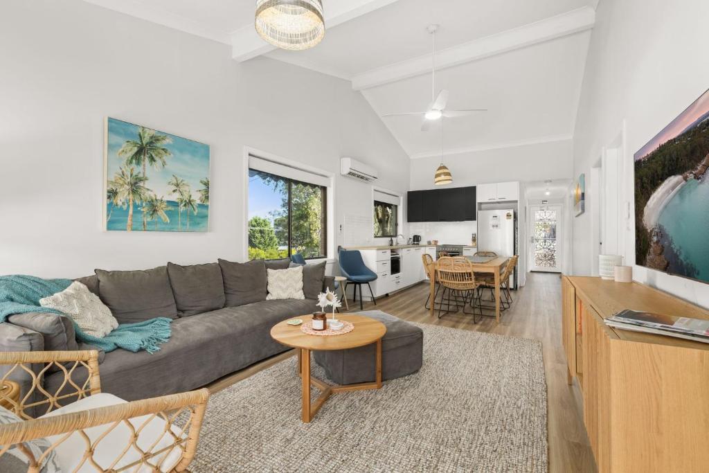 Una sala de estar con un sofá gris y una mesa. en Orion Retreat by Experience Jervis Bay, en Vincentia