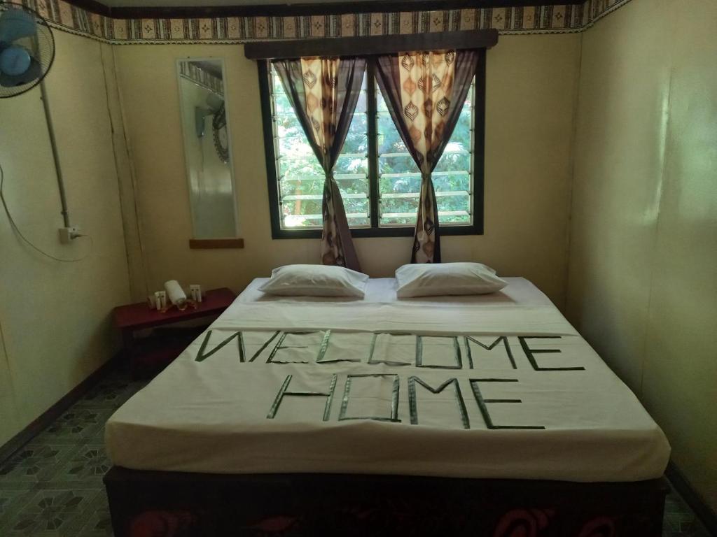 a bedroom with a bed with a welcome sign on it at WAI MAKARE HOMESTAY ROOM 2 in Naviti Island