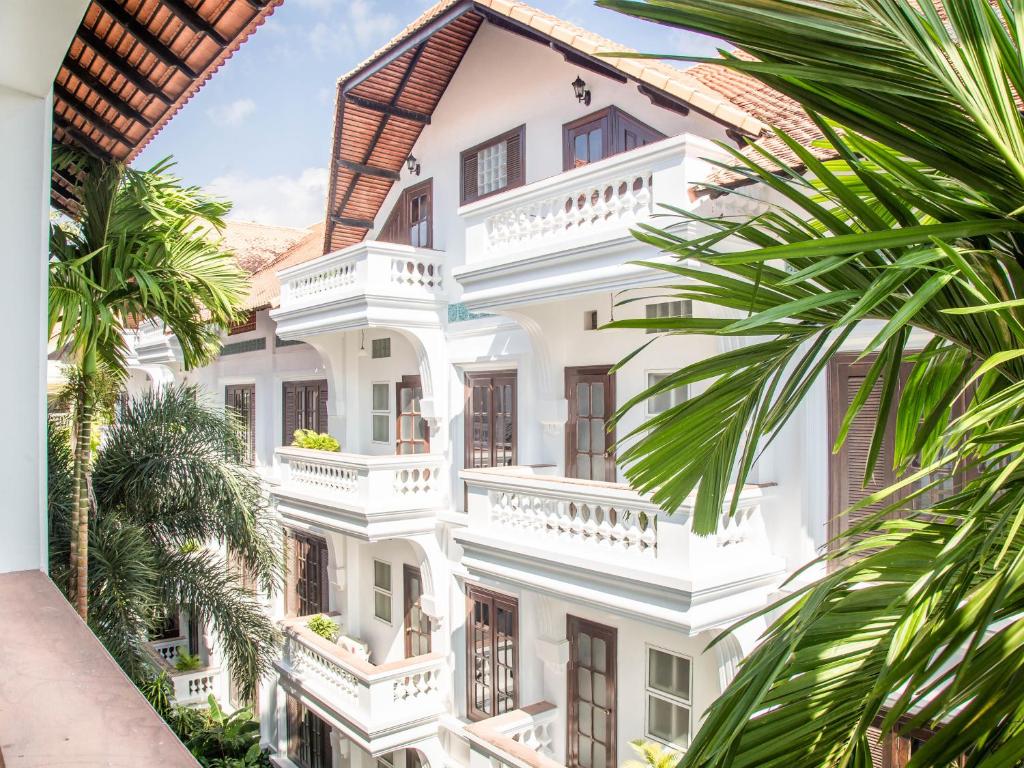 a white building with balconies and palm trees at Chateau d'Angkor La Residence in Siem Reap