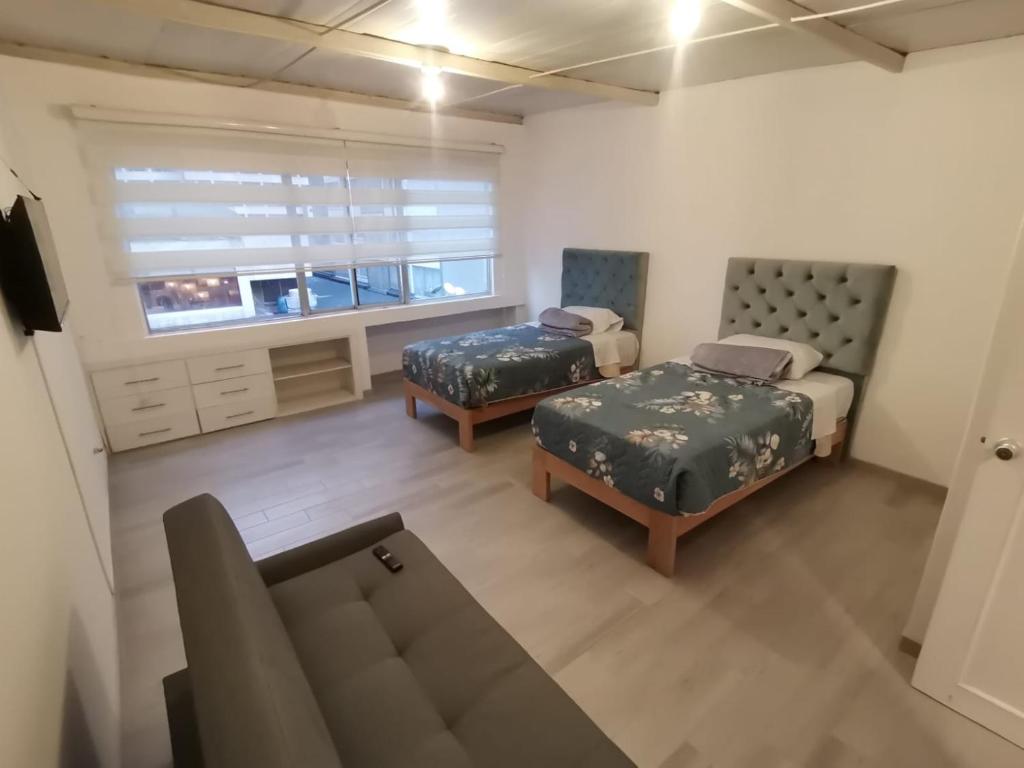 sala de estar con 2 camas y sofá en Suite Doble en Parque la Carolina, en Quito