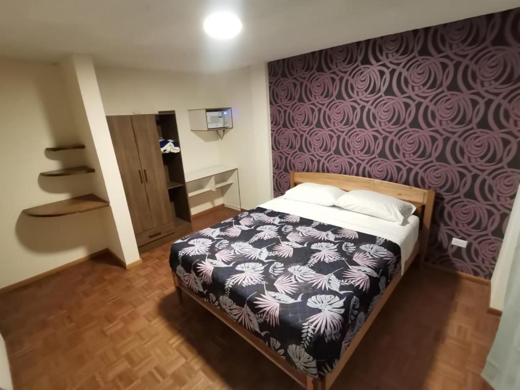 1 dormitorio con cama y pared púrpura en Dormitorio Amplio cerca de Parque Carolina, en Quito