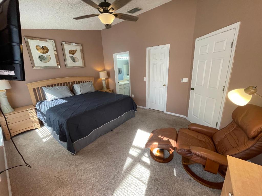 a bedroom with a bed and a couch and a television at 3 Bedroom Villa with Poolside Cinema and Games Room Close to theme Parks sleeps 6 plus 2 in Orlando