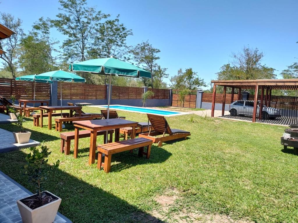 un gruppo di tavoli da picnic e ombrelloni accanto alla piscina di Complejo Monaco Calamuchita a Santa Rosa de Calamuchita