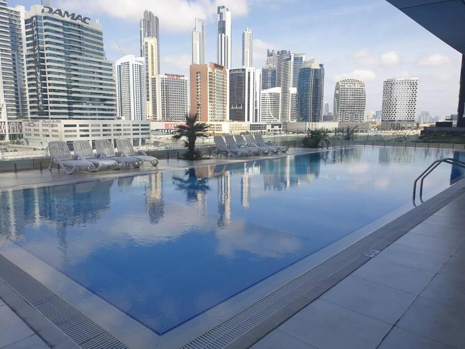 a large swimming pool with chairs and a city skyline at Large cozy Studio(Hamilton Residency) in Dubai
