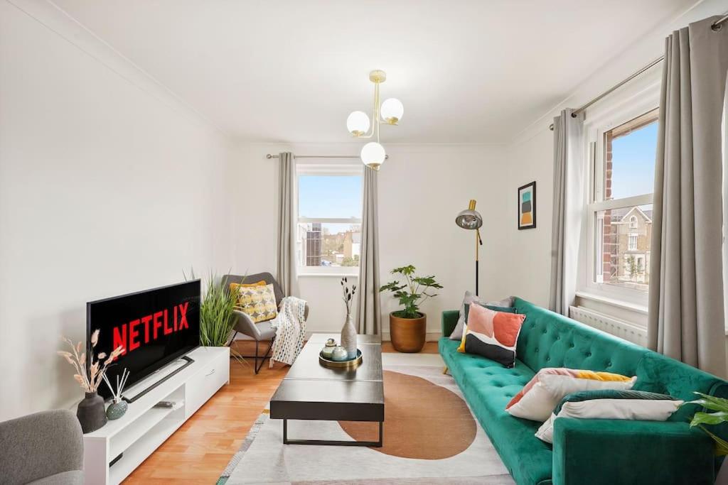 - un salon avec un canapé vert et une télévision dans l'établissement 5 guests 3 beds 1 sofa bed Lewisham, à Londres