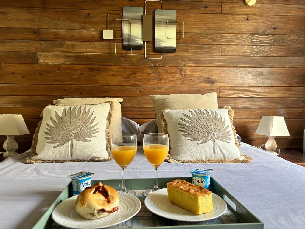 taca z dwoma kieliszkami soku pomarańczowego i ciastem na łóżku w obiekcie Villa Bharati - Plaine des Palmistes w mieście La Plaine-des-Palmistes