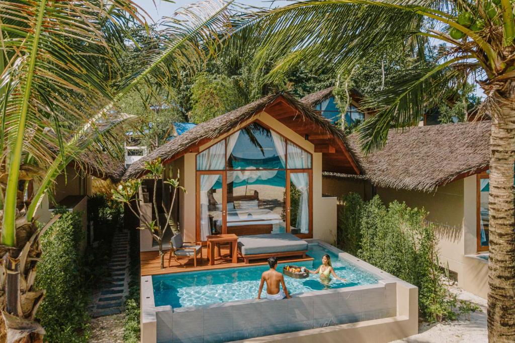 Irene Pool Villa Resort, Koh Lipe في كو ليبي: شخصين يلعبون في مسبح أمام منزل