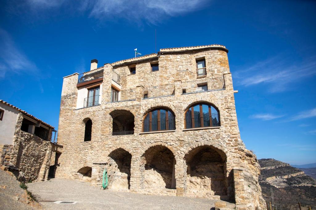 un gran edificio de piedra con ventanas en una colina en Casa Sanui. Apartaments turístics rurals, en Estorm