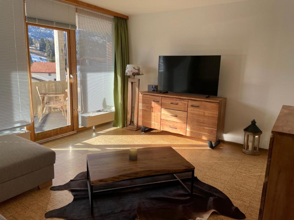 ein Wohnzimmer mit einem TV und einem Couchtisch in der Unterkunft 2 Zimmer Wohnung in Lenzerheide