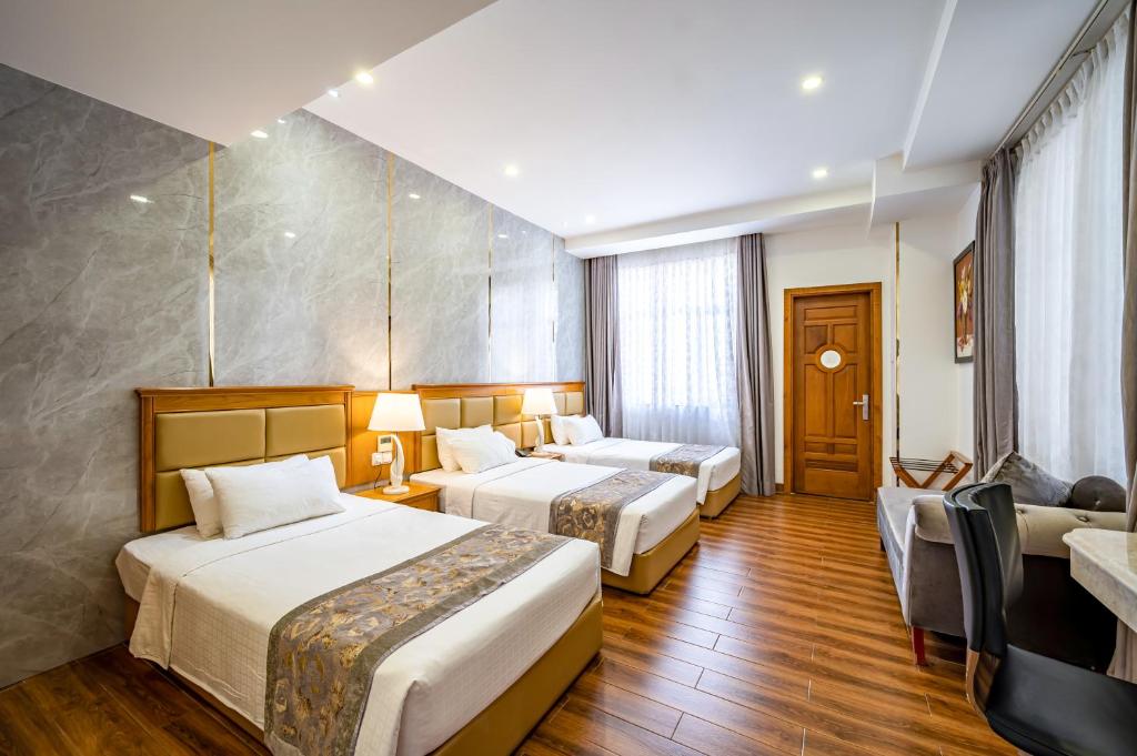 a hotel room with two beds and a couch at Acnos Grand Hotel in Ho Chi Minh City