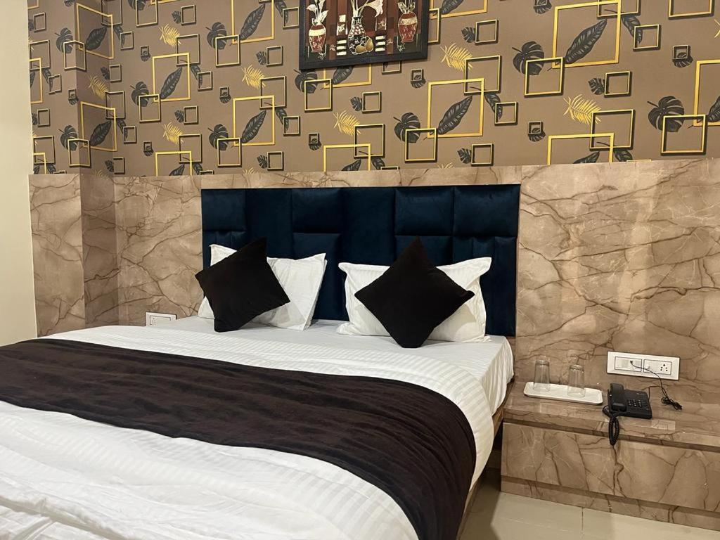 een slaapkamer met een groot bed met zwart-witte kussens bij HOTEL SUNRISE in Vadodara