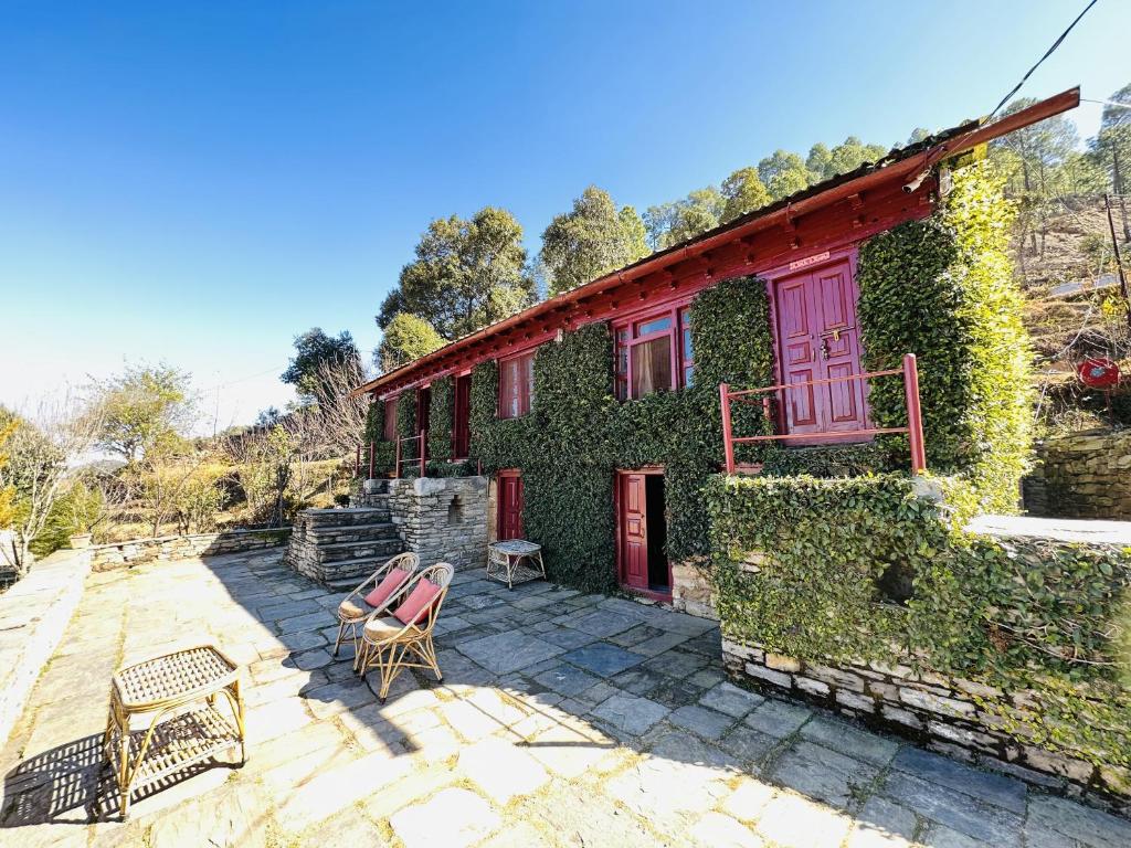 ein mit Efeu bedecktes Haus mit zwei Stühlen und einem Gebäude in der Unterkunft Itmenaan Estate in the Himalayas in Almora