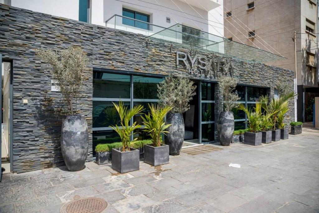 eine Reihe von Pflanzen vor einem Gebäude in der Unterkunft Rysara Hotel in Dakar