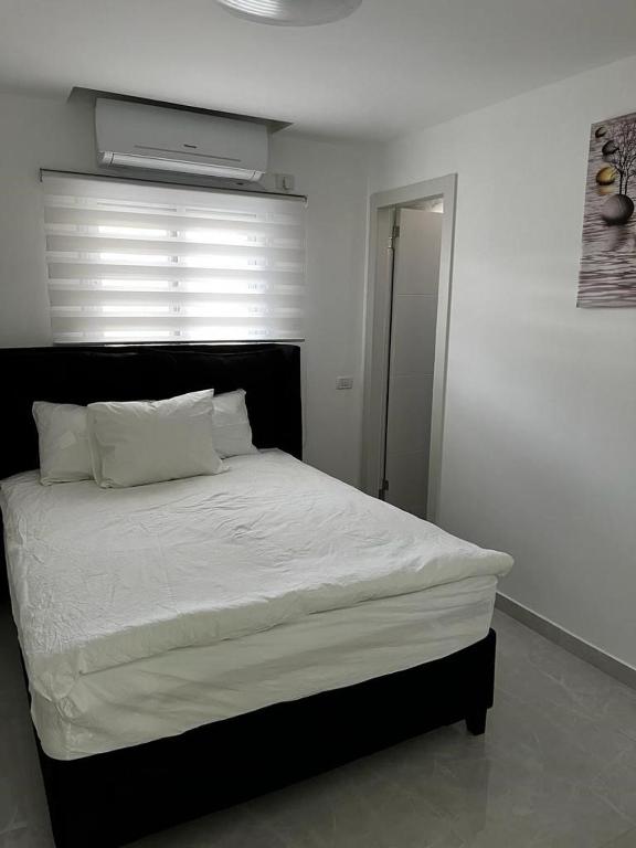 a bedroom with a white bed with a black headboard at מישל נופש ,צופית תחתית 6003 in Eilat