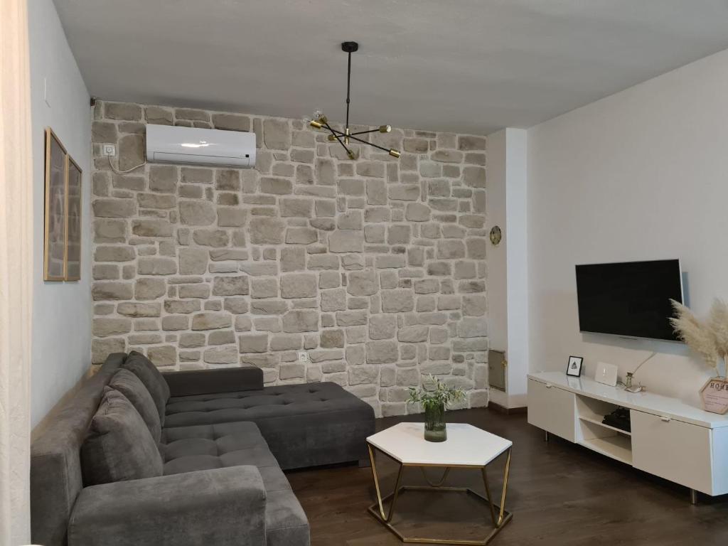 a living room with a couch and a stone wall at Casa sole infinito in Senj