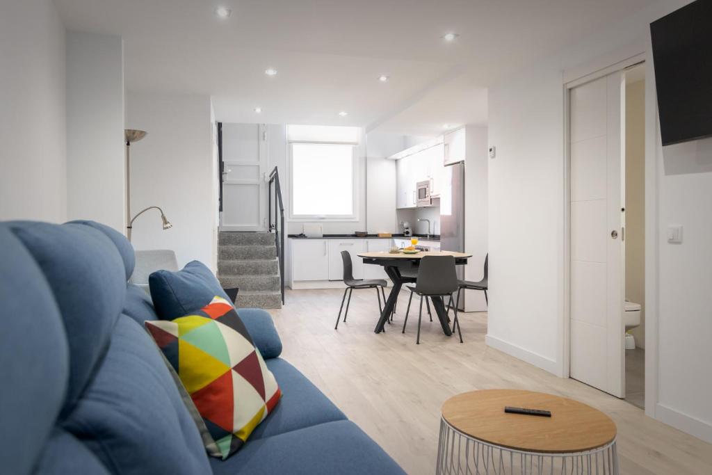 un soggiorno con divano blu e una cucina di Apartamentos Soria Suites a Soria