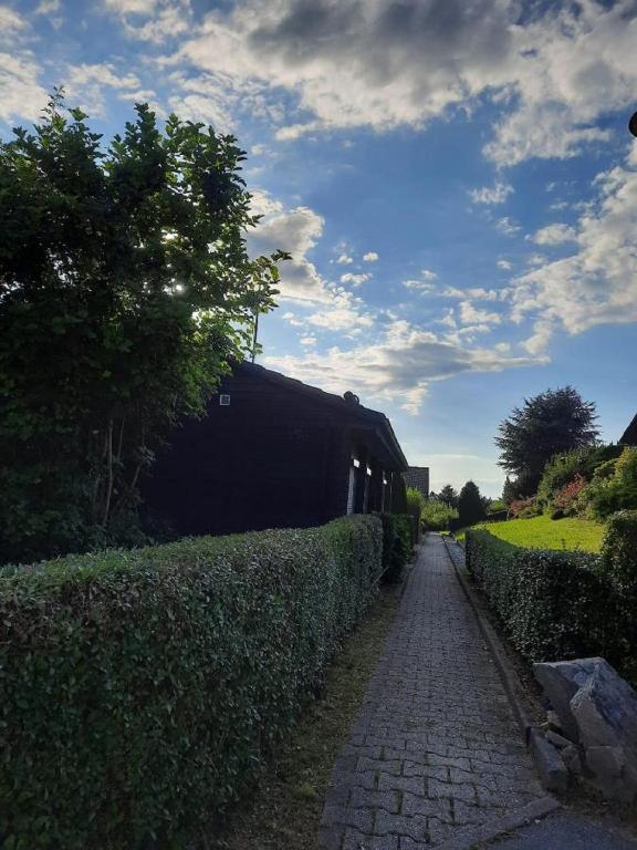 einen Kopfsteinpflasterweg neben einer Hecke mit einem Gebäude in der Unterkunft Ferienhaus Summerer in Grafenau