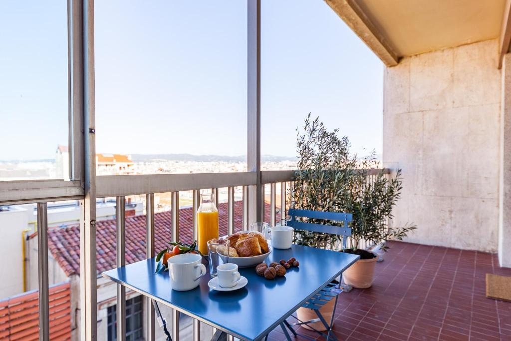 une table bleue avec un bol de nourriture sur un balcon dans l'établissement Sacha, à Marseille