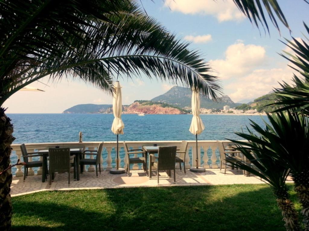 eine Terrasse mit einem Tisch und Stühlen neben dem Wasser in der Unterkunft Apartments Villa Mare Mar in Sutomore