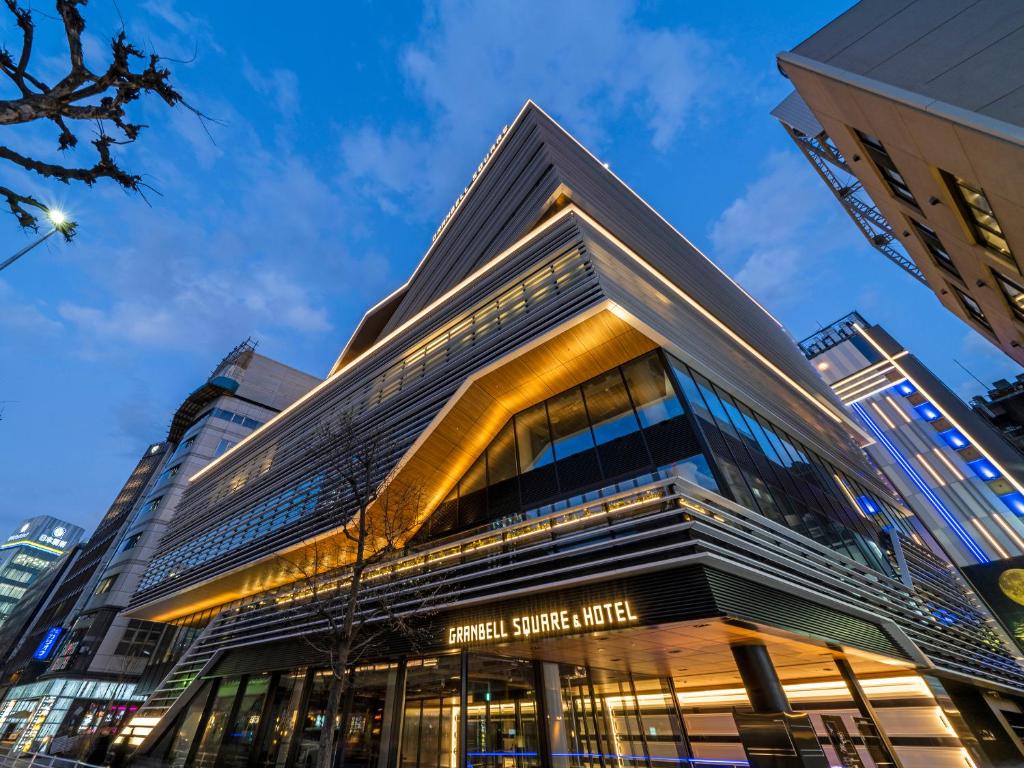 a tall building with glass windows in a city at GINZA HOTEL by GRANBELL in Tokyo