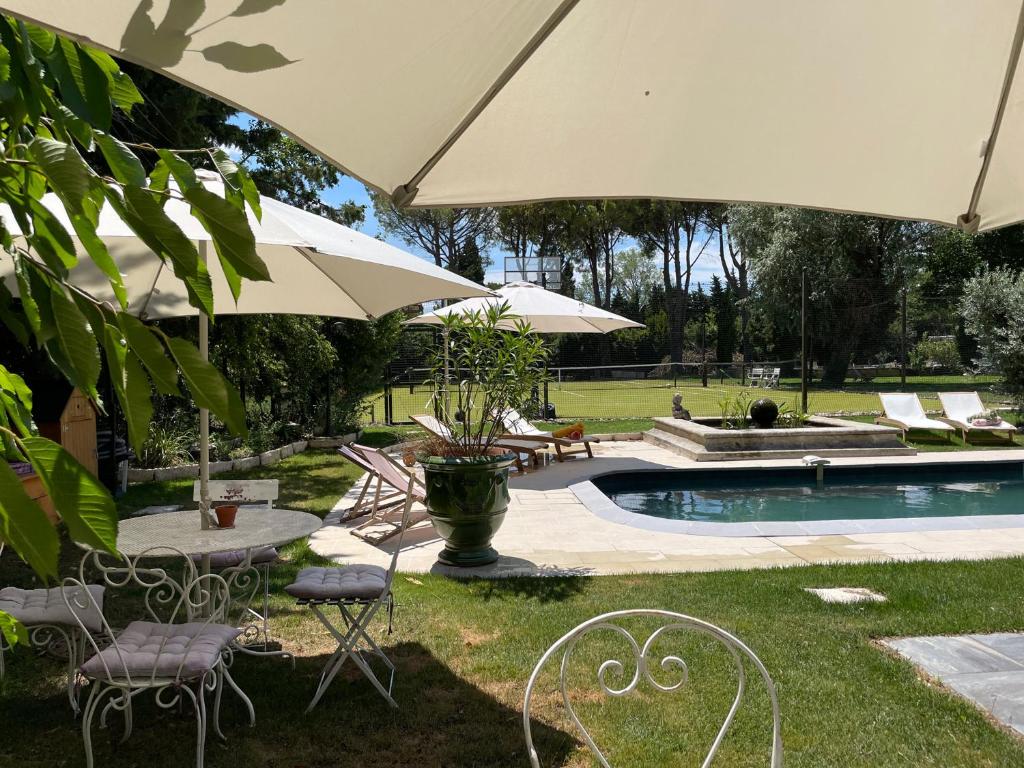 un patio avec des tables et des parasols à côté d'une piscine dans l'établissement Mas de la Sacristière, à Jonquerettes