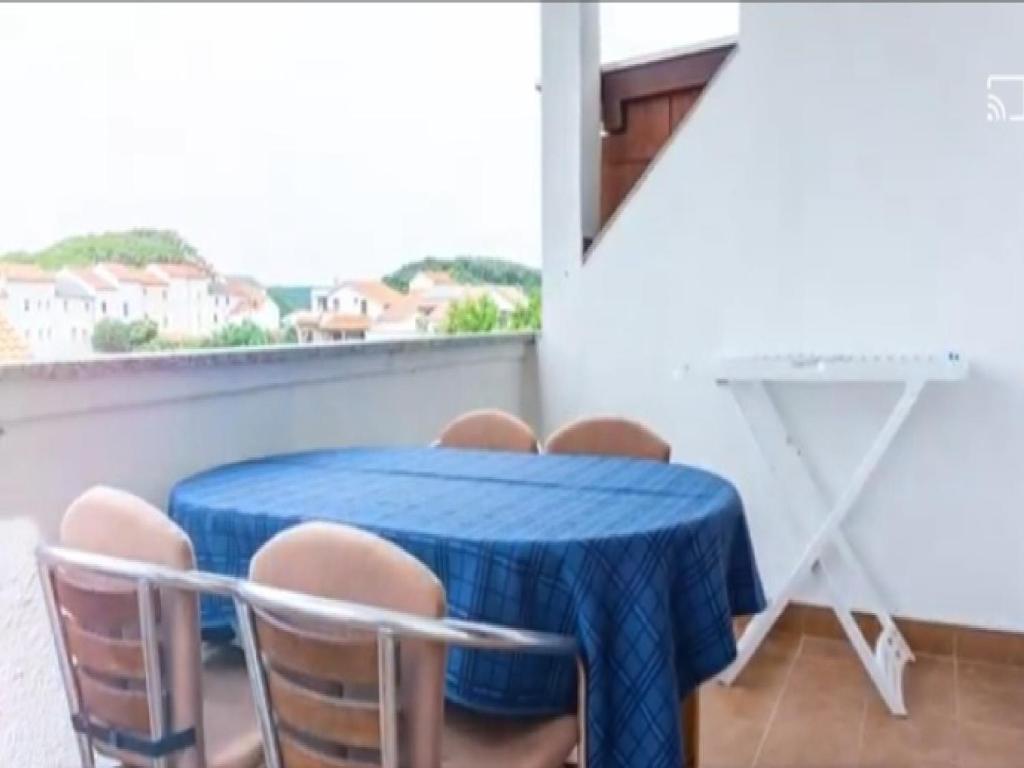 una mesa azul y sillas en una habitación con ventana en Apartments Snjezana, en Rab