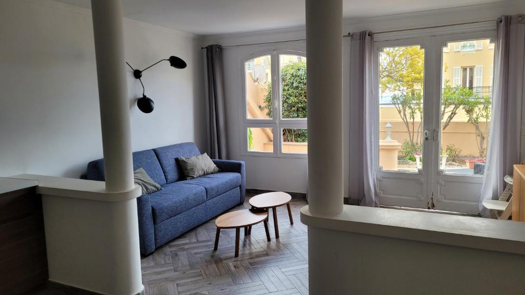 a living room with a blue couch and two windows at Appartement charmant et calme aux portes de Monaco in Cap d'Ail