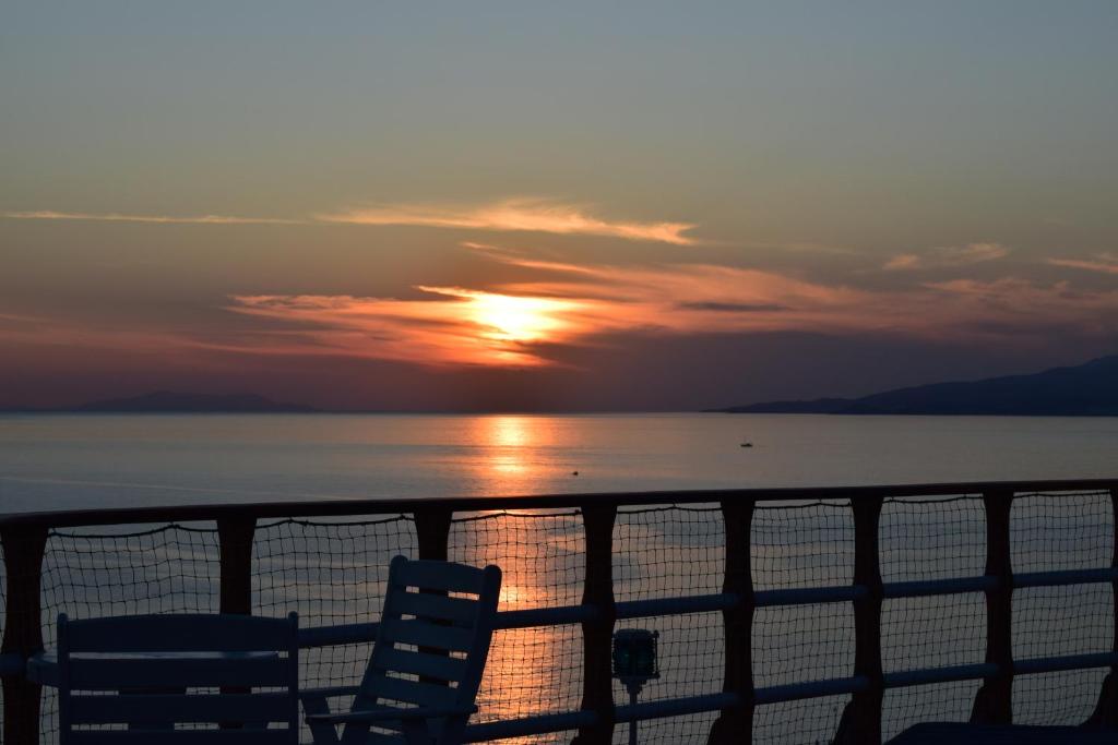 a sunset over the water with two chairs on a ship at Mykonos View Hotel in Mýkonos City