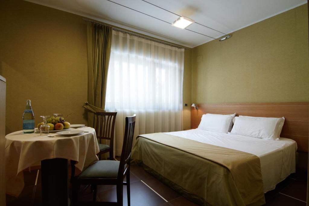sypialnia z łóżkiem, stołem i oknem w obiekcie Hotel Villa San Pietro w mieście San Giovanni Rotondo