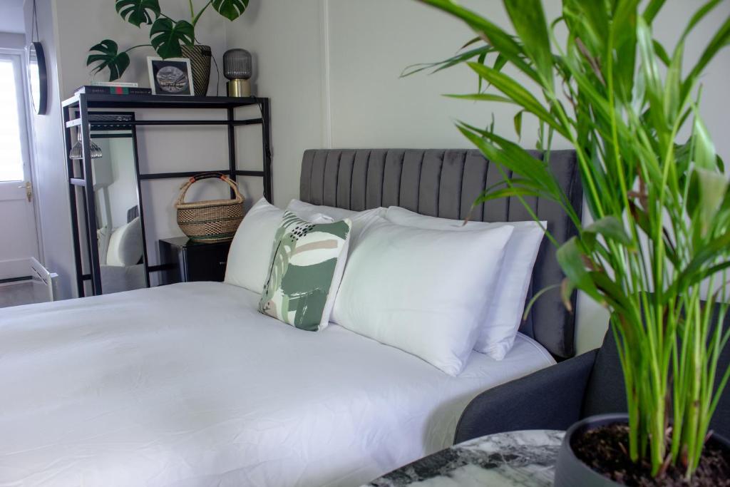 a bedroom with a bed with white pillows and a plant at Annex By The Sea in Littlehampton