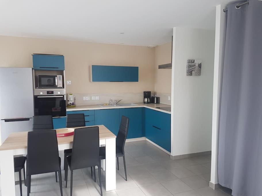 een keuken met blauwe kasten en een tafel en stoelen bij Maison au calme 2 à 300 m de la plage 2 chambres in La Cotinière