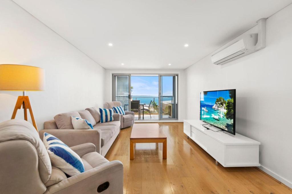 a living room with a couch and a flat screen tv at The Shoal in Shoal Bay