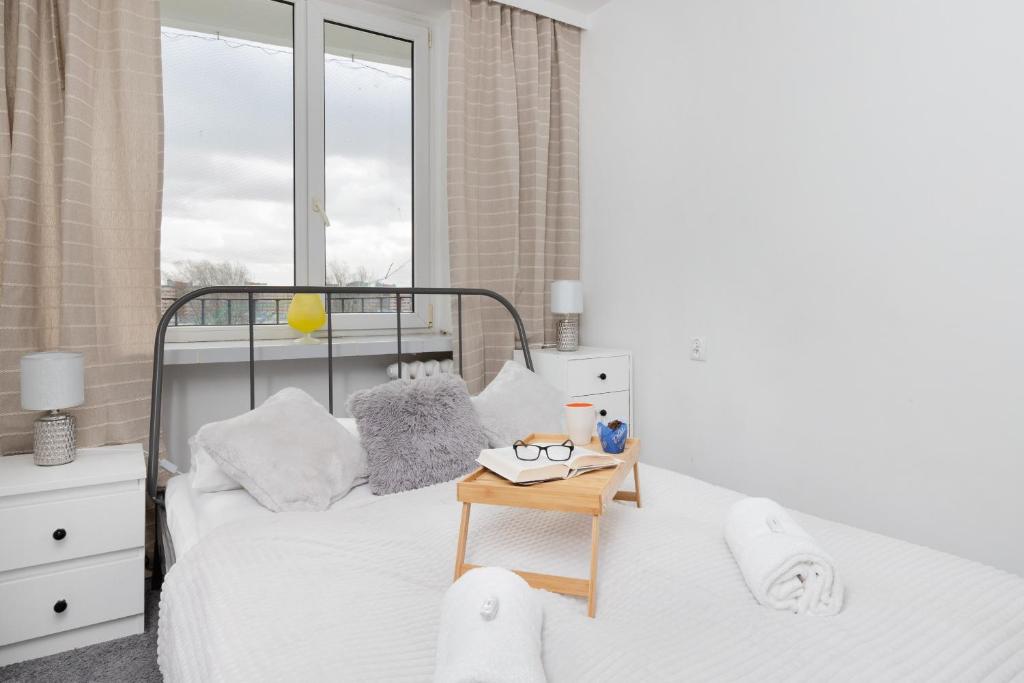 a white bedroom with a bed and a table at Przymorze Falowiec Apartment by Renters in Gdańsk