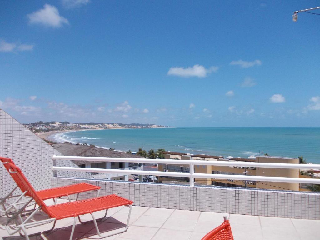 un balcón con un banco rojo y la playa en Varandas Praia de Ponta Negra, en Natal