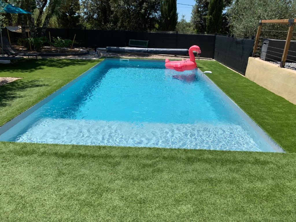 une piscine avec un flamingo rose dans l'herbe dans l'établissement Séjour détente et bien être avec SPA au gîte l Olipin, à Aubais