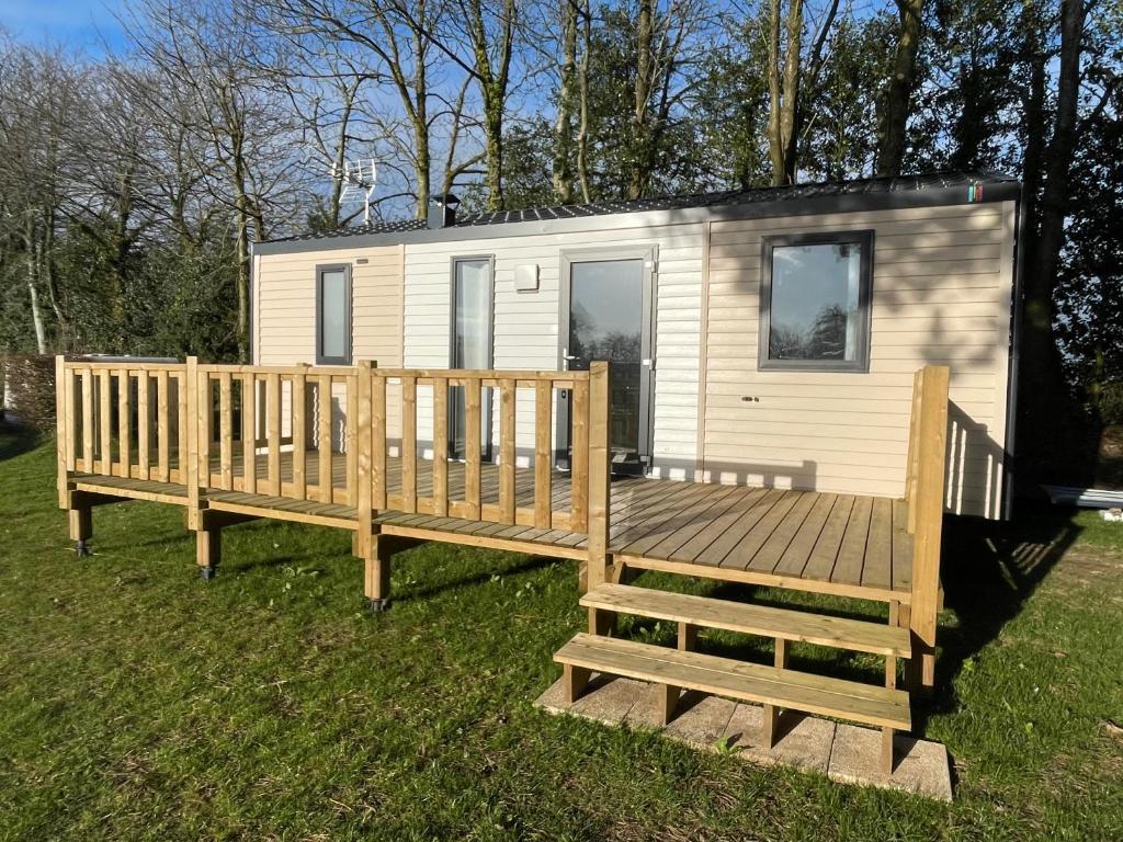 een tiny house met een groot terras in het gras bij Mobile-home Pin in Bec-de-Mortagne