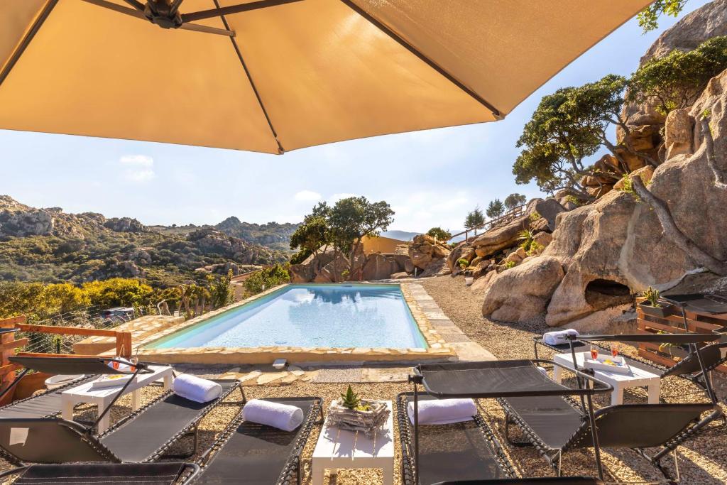 uma piscina com cadeiras e um guarda-sol em Villa Esmeralda - Free Wifi - with swimming pool em Costa Paradiso