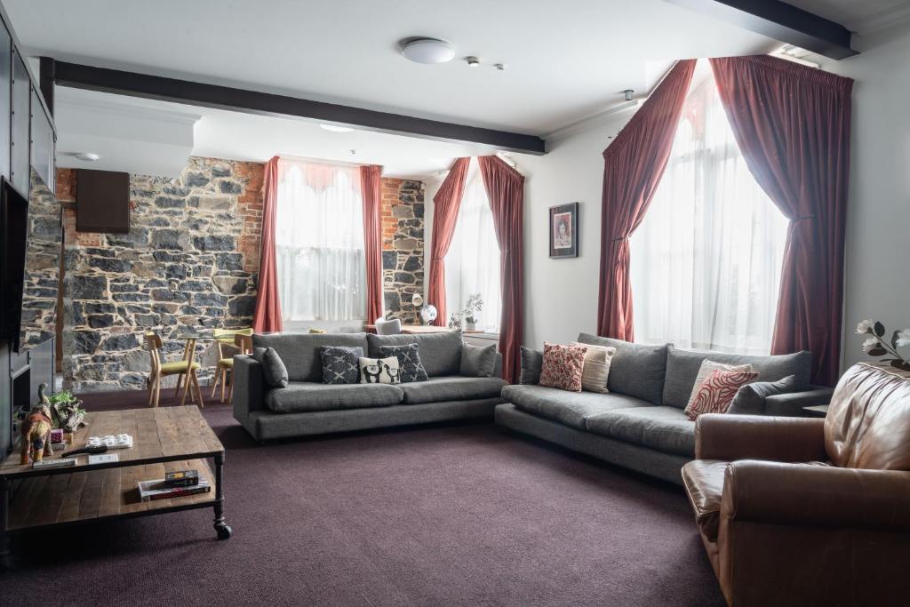 a living room with couches and a brick wall at Chapel Apartment in Dunedin