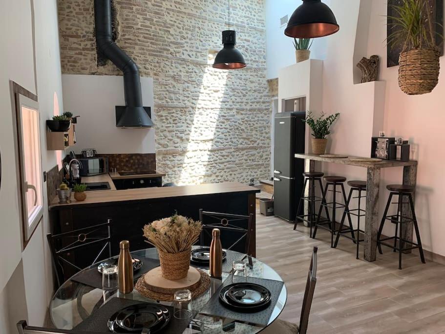 uma cozinha com uma mesa de vidro com cadeiras e um fogão em Cœur de ville em Perpignan