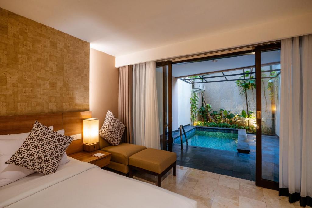 Cross Vibe Paasha Atelier Bali Kuta في كوتا: غرفة نوم بسرير وغرفة مع مسبح